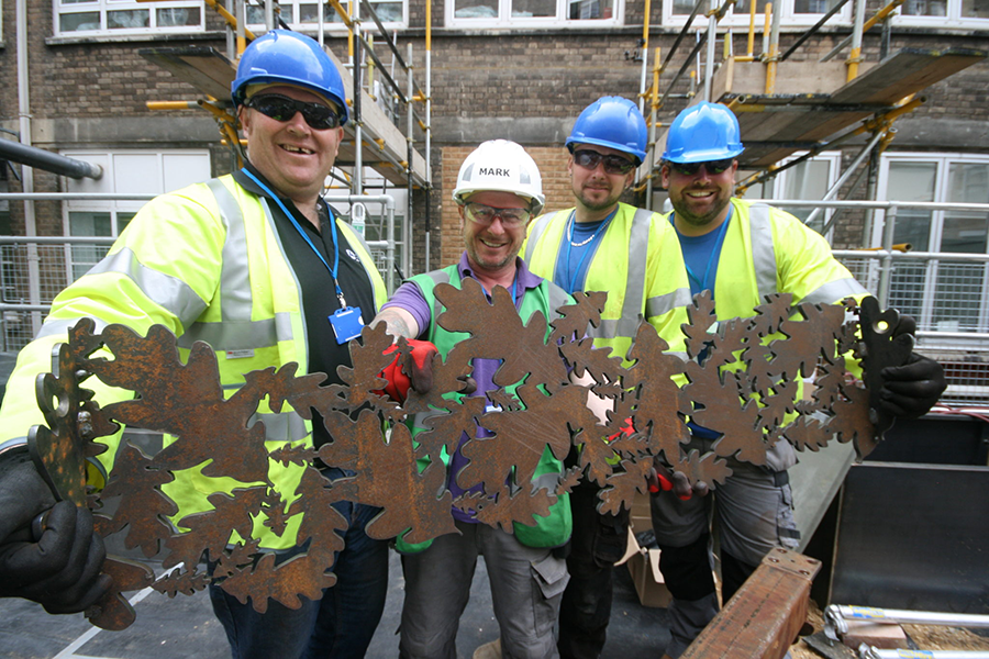 Il team di "DIY SOS: The Big Build" con in mano un elemento di una splendida pergola da giardino con motivo a foglie di quercia, realizzato nel sottotetto del Great Ormond Street Hospital da Nigel Ferguson Fabrications utilizzando la macchina per il taglio al plasma CNC Swift-Cut Pro